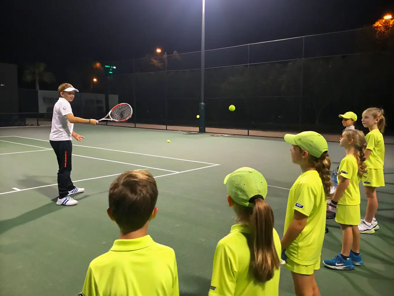 A coach demonstrating a serve to a group of adult players on a sunny outdoor court, focusing on technique and form.